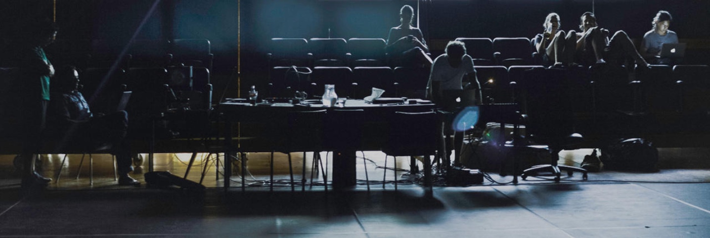 Performers and collaborators working in a dark theatre auditorium