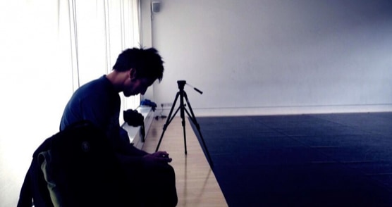 A seated figure and a camera silhouetted beside the rehearsal floor