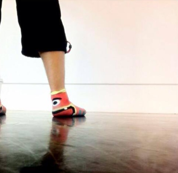 A performer wearing a colourful character sock on the rehearsal floor