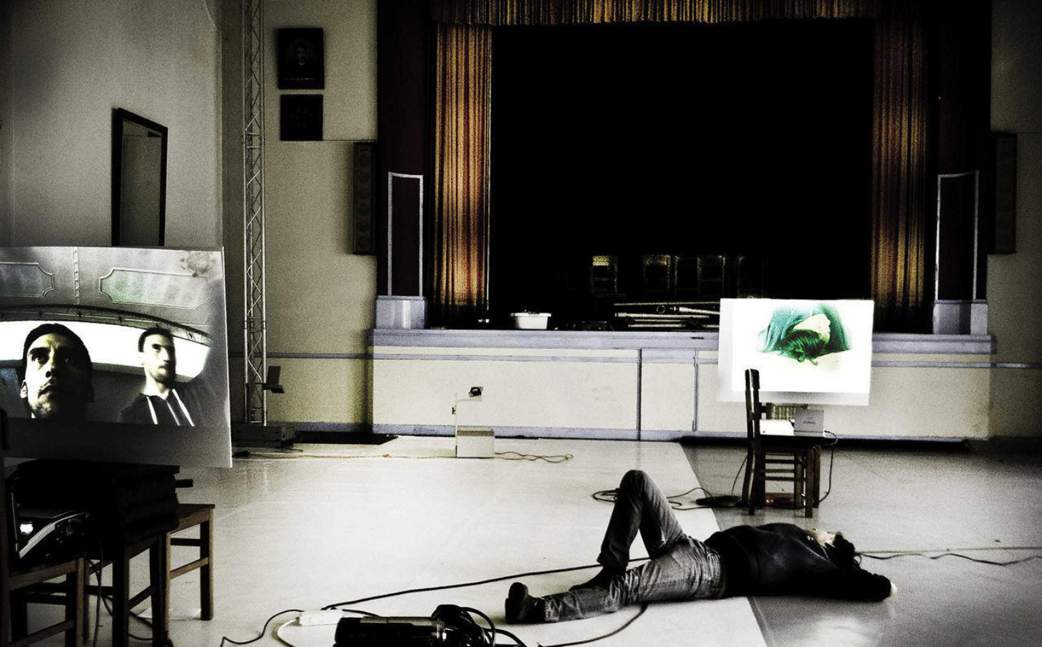 A performer lying on the floor between two projected images in the Convento da Saudação performance space